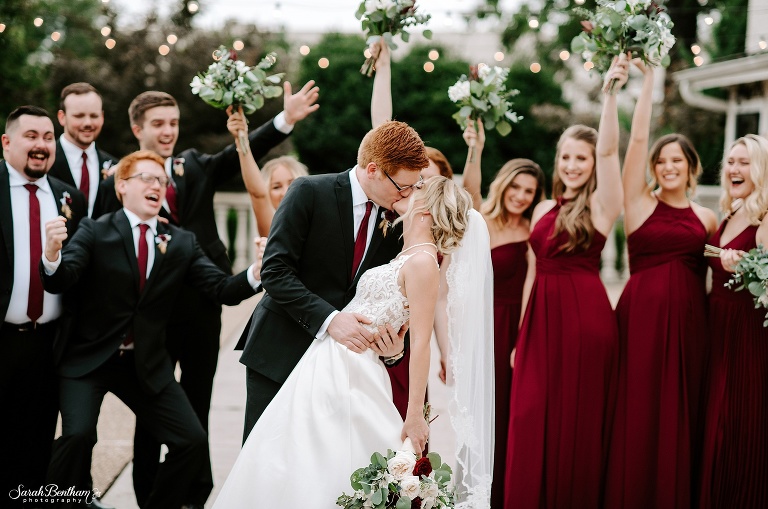 bride and groom kiss as bridal party cheers